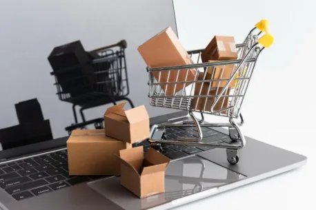 Wózek zakupowy z paczkami na laptopie – symbolizujący sklep internetowy i e-commerce z wykorzystaniem Gorilla Commerce